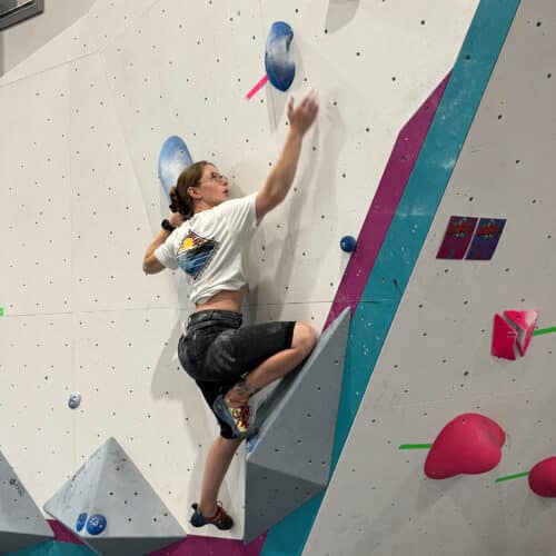 A person climbing up a rock wall in a climbing gym.